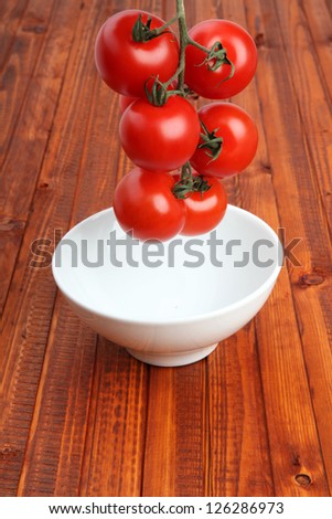 Stem of tomatoes pulled down into a bowl by gravity