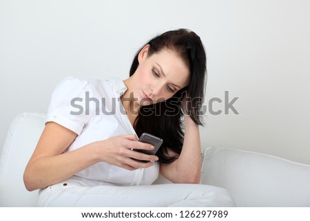 Young woman with bored expression looking at message on her cell phone