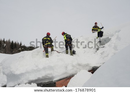 Madesimo, Italy- February 13,2014: Fireman free the roofs from the heavy snow caused by the bad weather that hurts the Italian alps this winter