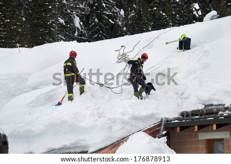 Madesimo, Italy- February 13,2014: Fireman free the roofs from the heavy snow caused by the bad weather that hurts the Italian alps this winter
