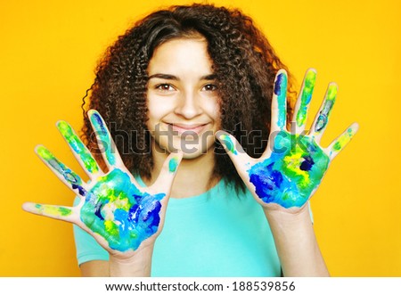 Pretty Latino American young girl with painted hands like a map of the earth .  Happy girl with painted hands.