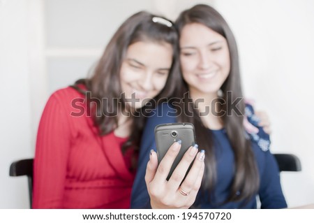 Two young women taking picture of themselves on a mobile phone.