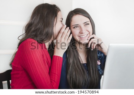 Two  young girls  discuss something. One girl whispers  something to other girl.