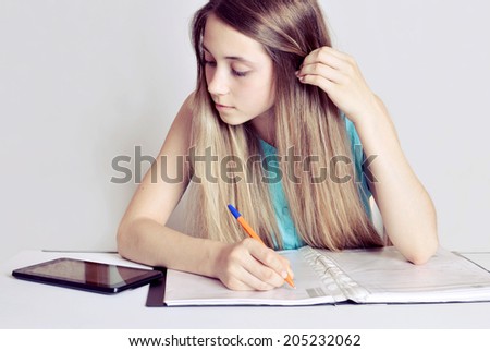 Studying cheerful  teenager girl with Digital Tablet . Cheerful  teenager girl reading her book for school and making notes.