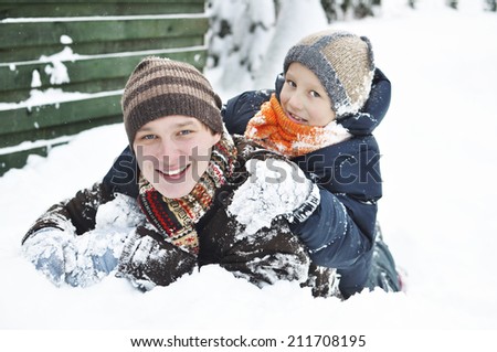 Happy family in the winter. Young father playing with son in the snow. It\'s snowing.