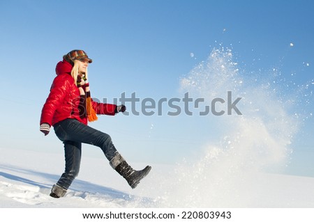 Pretty girl enjoys winter. Young girl throws snow footed in sunny winter day.