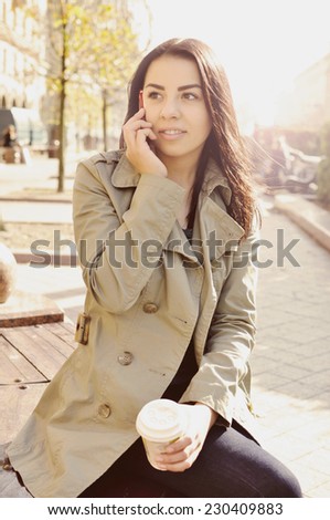 Beautiful teenage girl talking on the phone in the city. Beautiful teenage girl with phone and coffee. Phone call.