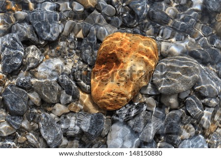 golden and grey stones in the river with sunbeam reflecting and moving water