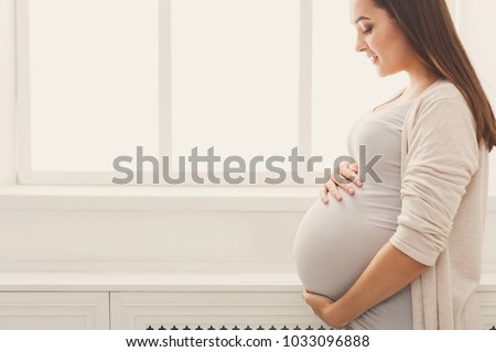 Pensive pregnant woman dreaming about child. Young happy expectant thinking about her baby and enjoying her future life. Motherhood, pregnancy, happiness concept, copy space