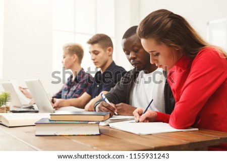 Multiethnic university students studying together. Young people working with tests and gadgets at wooden table. Education and technology concept, copy space