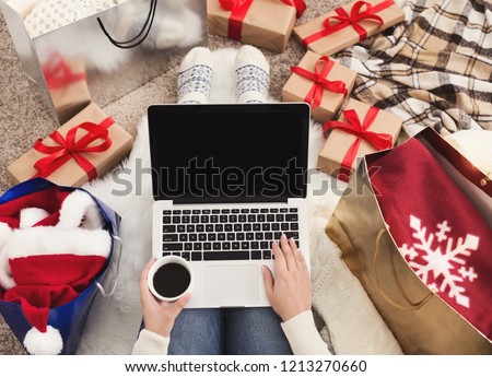 Preparing for Christmas party. Woman ordering presents and decorations on laptop, sitting among gifts boxes and packages, copy space