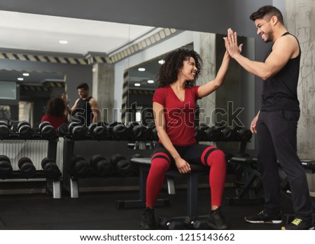 Successful training. Fitness trainer and woman giving each other high five after workout in gym, copy space