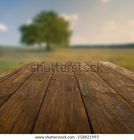Wooden table outdoors with autumn field and tree background