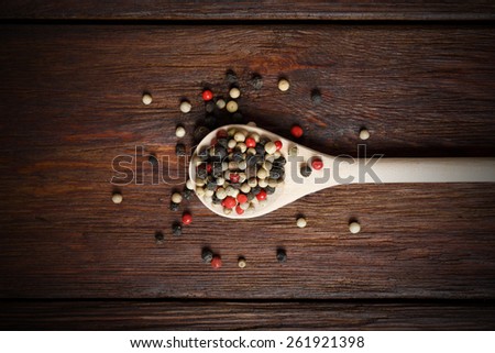 Mix of pepper seasoning in a wooden spoon close-up on the wood