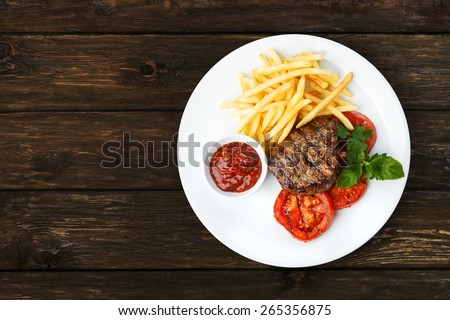 Restaurant food - beef grilled steak isolated at the wooden table, above view