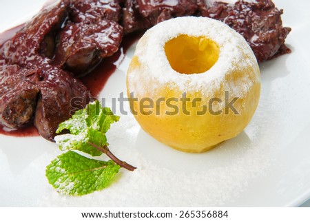 Restaurant food - chicken liver in pomegranate sauce with baked apple close-up