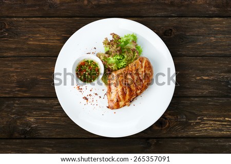 Restaurant food - chicken fillet grilled steak at wooden table