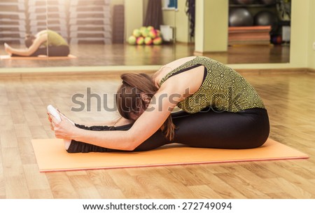 Young flexible woman in a yoga stretching head to knee pose