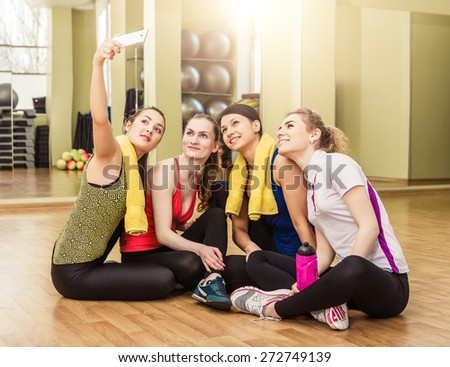 Group of girls in fitness class at the break looking at smartphone