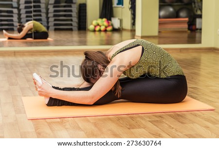 Young flexible woman in a yoga stretching head to knee pose