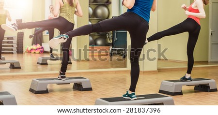 Group of women making step aerobics in fitness club - view from the backside