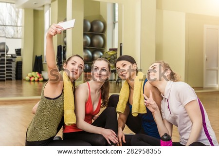 Group of girls in fitness class at the break looking at smartphone