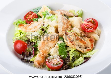 Restaurant food - salad with roasted chicken fillet, lettuce mix, cherry tomatoes and parmesan, closeup at white plate