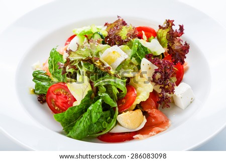 Restaurant healthy food, diet nutrition - fresh salad with salmon, quail eggs, cherry tomatoes and lettuce, closeup