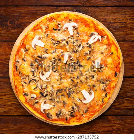 Delicious pizza with mushrooms - thin pastry crust isolated at wooden background, above view