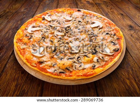 Delicious pizza with mushrooms - thin pastry crust isolated at wooden background