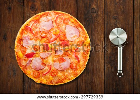 Delicious pizza with peppers, bacon and cherry tomatoes - thin pastry crust isolated at white background with stainless steel cutter, above view