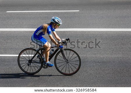 Female sportsman cyclist riding racing bicycle. Woman cycling on countryside road or highway. Training for triathlon or cycling competition.