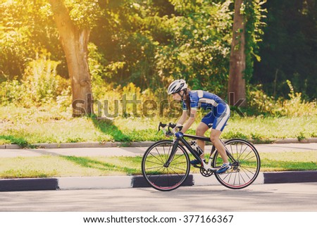 Female sportsman cyclist riding racing bicycle. Woman cycling on countryside summer sunny road or highway. Training for triathlon or cycling competition.