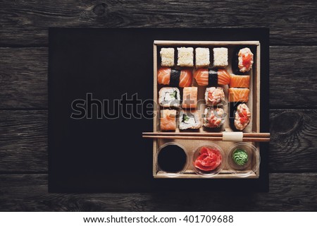 Japanese food restaurant, sushi maki gunkan roll plate or platter set. Free, copy space, chopsticks, ginger, soy sauce, wasabi. Sushi at rustic wood background in take away, delivery box. Top view.