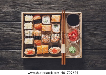 Japanese food restaurant, catering, sushi maki gunkan roll plate or platter set. Chopsticks, ginger, soy sauce, wasabi. Sushi at rustic wood background in take away, sushi set delivery box. Top view.