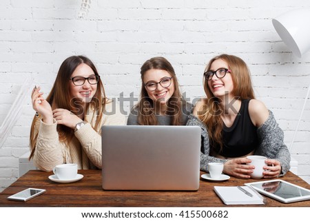 Portrait of three laughing girlfriends with laptop. Young girls friends happy together with computer. Women  friendship, modern life, gossip and internet dating concept. Technology and people.