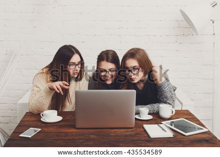 Three girls work and coffee with laptop. Young girls friends happy with computer. Discussion, startup, friendly conversation. Women friendship, modern life, gossip and internet dating concept.