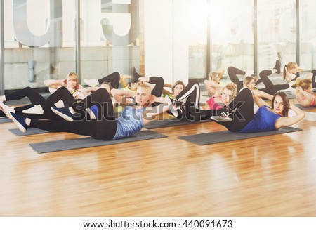 Group of young women in fitness class. Group of people making exercises. Girls do cross crunches for abs. Healthy lifestyle, training, sport, gym studio. Sporty girls in fitness club, aerobics.