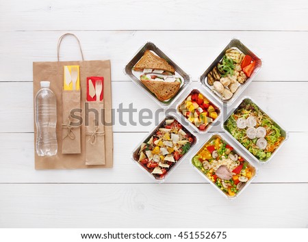 Healthy food delivery. Take away for diet. Fitness nutrition, vegetables, meat and fruits in foil boxes, cutlery, water and brown paper package. Top view, flat lay at white wood with copy space