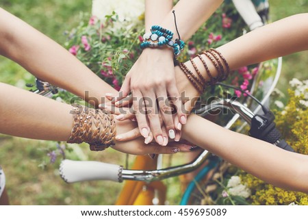 United hands of young females. Stylish hands of girlfriends in boho hippie bracelets near bicycle handlebar, top view. Togetherness and support, youth fashion and active lesiure. Women friendship