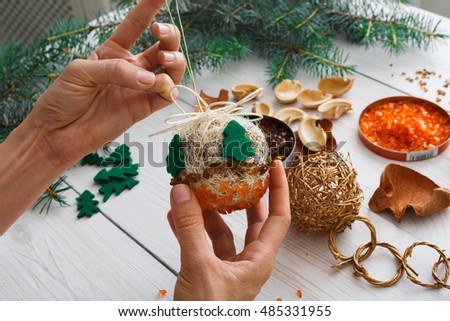 Creative diy craft hobby. Making handmade craft christmas ornaments and balls with felt spruce tree. Woman\'s leisure, holiday decorations. Closeup of female hands at white wood background