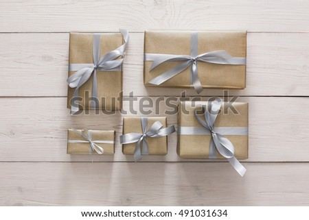 Top view of Gift boxes on white wood background. Presents in craft paper decorated with stylish elegant silver satin ribbon bows. Christmas and any other holidays concept, top view, flat lay