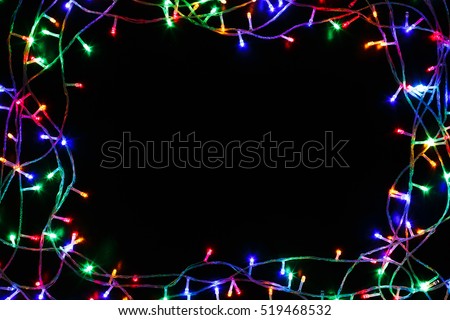 Christmas lights frame on black background. Holiday shiny garland border top view. Xmas tree decorations, winter holidays illumination