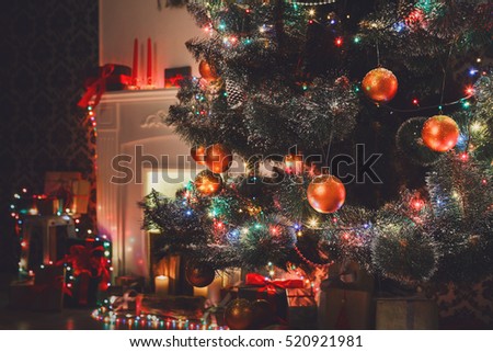 Christmas living room decorations, fireplace closeup. Beautiful xmas lights, candles, illuminated decorated christmas tree in garlands. Modern interior design, winter holidays magic night atmosphere.