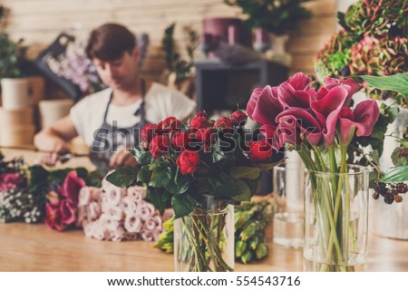 Small business. Male florist unfocused in flower shop. Floral design studio, making decorations and arrangements. Flowers delivery, creating order