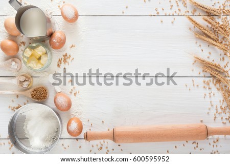 Baking background. Cooking ingredients for yeast dough and pastry, eggs, flour and milk on white rustic wood. Top view with copy space, mockup for menu, recipe or culinary classes.