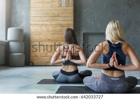 Women in yoga class making asana exercises. Girls do Reverse Prayer Pose, back and shoulders stretching. Healthy lifestyle in fitness club.