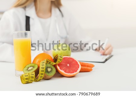 Nutritionist desk with healthy fruits, juice and measuring tape. Dietitian working on diet plan. Weight loss and right nutrition concept
