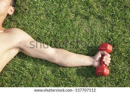 Close Up on Arm and Shoulder Holding Dumbbell in Grass