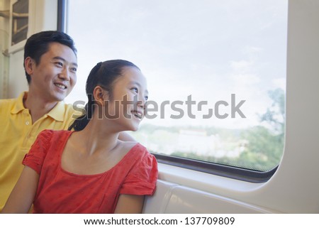Father and daughter looking through the window in the subway